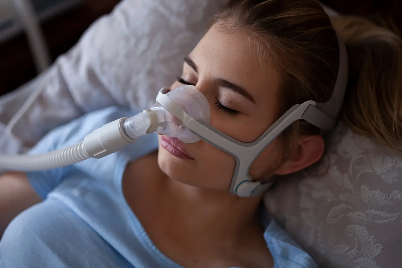 oxysphair-effets_secondaires_machine_apnee_du_sommeil Femme dormant paisiblement avec un masque CPAP, utilisé pour le traitement de l'apnée du sommeil.