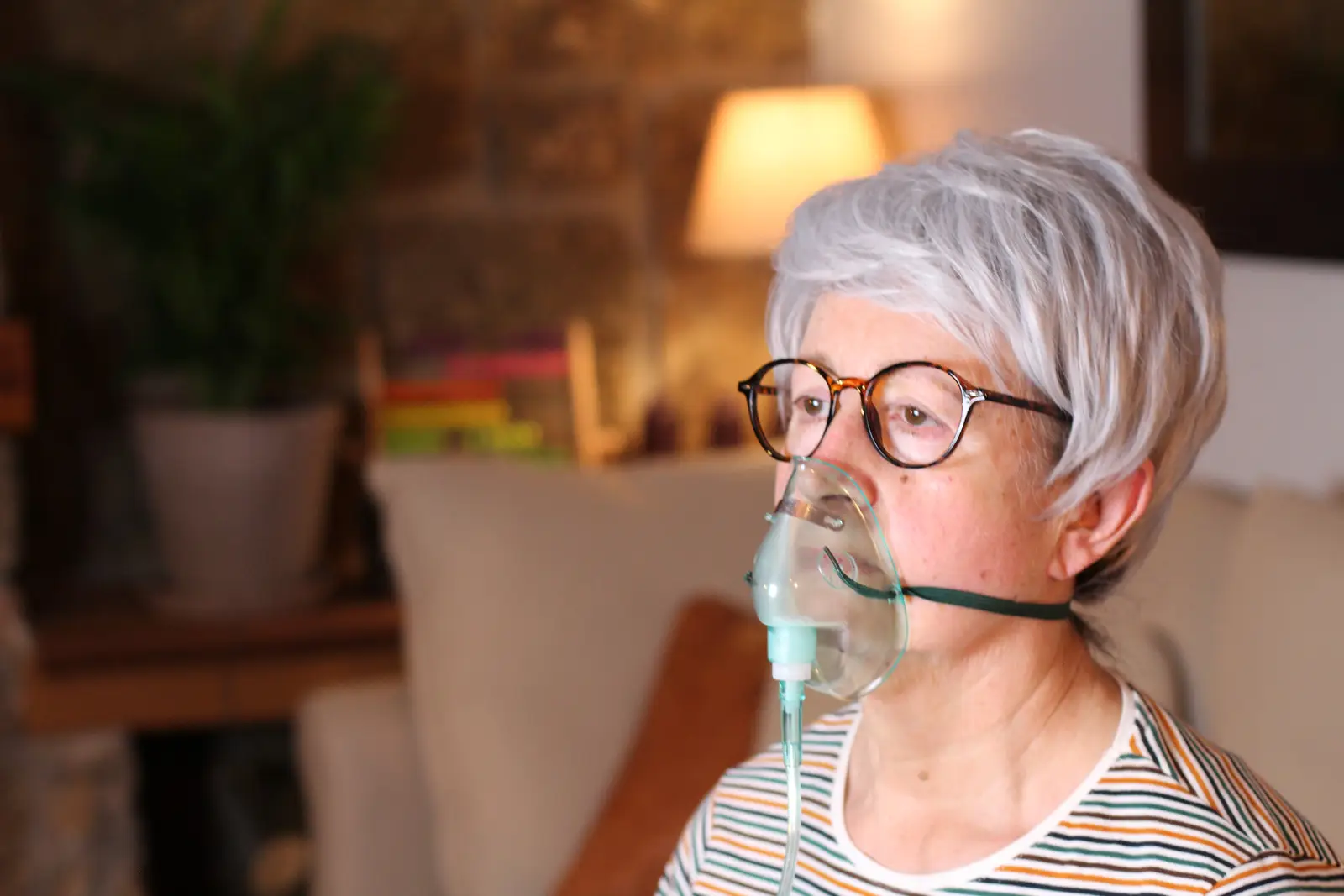 oxysphair-taux_oxygene_sang Femme portant un masque à oxygène chez elle, recevant un traitement d'oxygénothérapie pour des problèmes respiratoires.